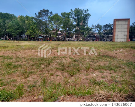 Empty dirt and grass field overlooking a street with trees, motorbikes, and a blank sign. Empty dirt and grass field overlooking a street with trees, motorbikes, and a blank sign. 143626067