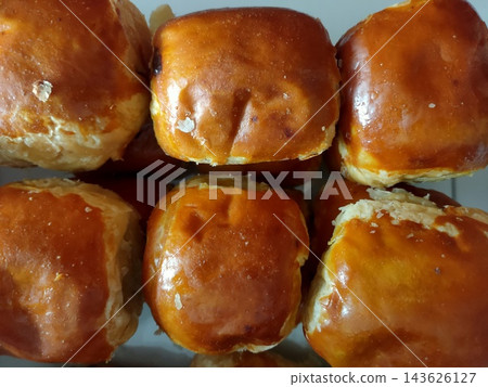 Freshly baked golden buns with a shiny egg-wash glaze. Delicious bakery snack 143626127