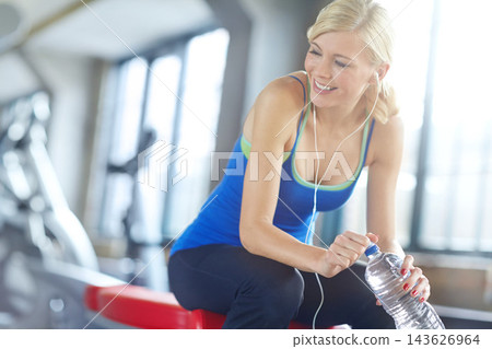 Fitness, music and water with woman in gym for break, thinking about health, wellness or workout. Bottle, exercise and smile with happy young person at training center for physical improvement Fitness, music and water with woman in gym for break, thinking about health, wellness or workout. Bottle, exercise and smile with happy young person at training center for physical improvement 143626964