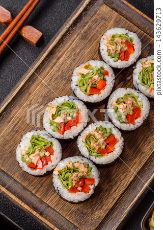 Salmon futomaki sushi roll with vegetables, soy sauce, wasabi, and ginger. Salmon futomaki roll 143629713