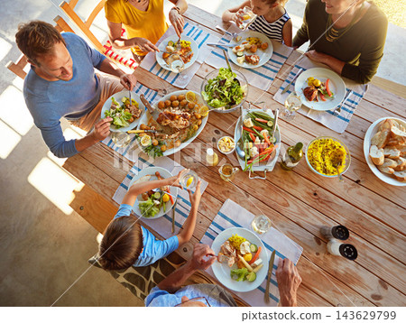 Table, food and top view of family for lunch, supper and eating meal at home together. Celebration, parents and children with dish for bonding, relax and talking for nutrition, health and wellness Table, food and top view of family for lunch, supper and eating meal at home together. Celebration, parents and children with dish for bonding, relax and talking for nutrition, health and wellness 143629799