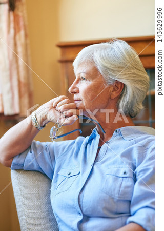 Window, senior or woman thinking in house with memory, ideas and calm peace on living room chair. Nostalgia, remember or elderly lady with decision, glasses or wellness in retirement, lounge or home 143629996