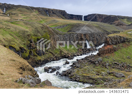 Hengifossa river rapids and distant Hengifoss in the summer landscape of Iceland Hengifossa river rapids and distant Hengifoss in the summer landscape of Iceland 143631471
