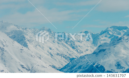 Panoramic snow-covered Mount Elbrus and surrounding Caucasus ridges beneath pale blue sky Panoramic snow-covered Mount Elbrus and surrounding Caucasus ridges beneath pale blue sky 143631707