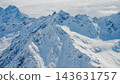 Aerial view of snow-covered Mount Elbrus and jagged Caucasus ridgelines under overcast sky 143631757