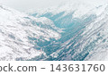 Aerial view of snow-covered Mount Elbrus and forested Caucasus valley under pale winter light 143631760