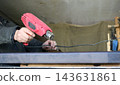 A craftsman holds a powerful red heat gun over a dark countertop edge, carefully managing the position of the power cord. The hot air helps dry the glue, varnish, or protective oil more quickly. 143631861