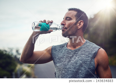 Fitness, athlete and man drinking water on break to hydrate or relax for healthy energy in exercise. Tired, fatigue and thirsty runner with liquid or bottle in marathon training or outdoor workout 143634883
