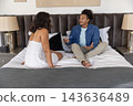 Couple sitting on bed, woman in white nightdress, man holding pregnancy test stick 143636489