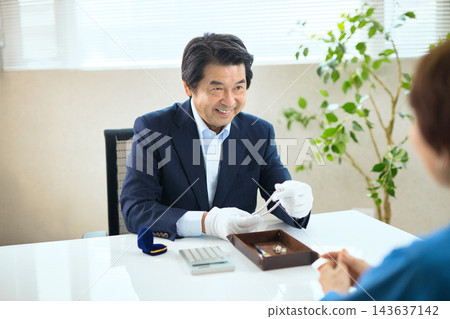 一位專門評估貴金屬的專業買家和一位資深女性 一位專門評估貴金屬的專業買家和一位資深女性 143637142