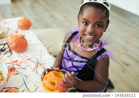 Portrait, child and princess costume for halloween, birthday or party at event as kids to celebrate. Girl, cheerful and creative with pumpkin for decor, fantasy or holiday tradition as youth in home Portrait, child and princess costume for halloween, birthday or party at event as kids to celebrate. Girl, cheerful and creative with pumpkin for decor, fantasy or holiday tradition as youth in home 143638121
