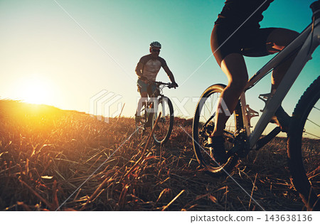 Sunset sky, people and friends on bicycle with fitness, race and adventure trail in nature together. Cycling, exercise and team with mountain bike in evening for outdoor workout, sun and countryside Sunset sky, people and friends on bicycle with fitness, race and adventure trail in nature together. Cycling, exercise and team with mountain bike in evening for outdoor workout, sun and countryside 143638136