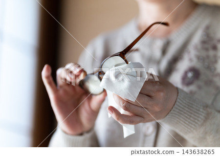 中老年婦女用布擦拭老花眼鏡。 中老年婦女用布擦拭老花眼鏡。 143638265