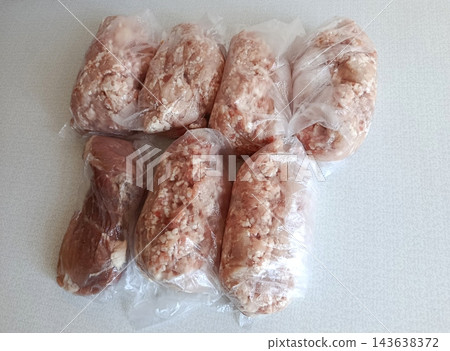 Various portions of raw minced pork and beef in clear plastic bags, prepared for freezing and bulk storage, facilitating meal preparation and efficient food management 143638372