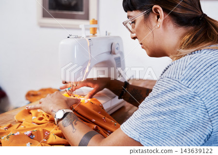 Woman, tailor and sewing machine on table in home for manufacturing, production and handmade costume. Creative, business owner or female sewer with garment, needle and textile with details to design 143639122