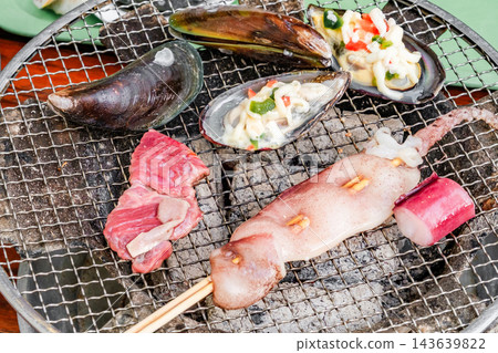 seafood is cooked on a charcoal grill seafood is cooked on a charcoal grill 143639822