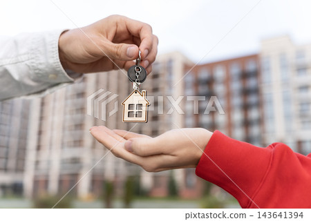 Closeup Of Woman Receiving Keys With House Keychain Outside Apartment Building. Mortgage Financing, Home Loan And Becoming A Homeowner Concept. Closeup Of Woman Receiving Keys With House Keychain Outside Apartment Building. Mortgage Financing, Home Loan And Becoming A Homeowner Concept. 143641394