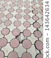 Outdoor paved walkway featuring a geometric tessellation of circular pink-red and star-patterned grey concrete tiles. The aged surface shows wear, cracks, and weeds in the joints. 143642634