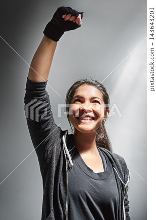 Woman, fist and air for winning and fitness, success for training and gym on gray background. Celebration, smile and wellness goals for person, gloves and achievement with power gesture in studio Woman, fist and air for winning and fitness, success for training and gym on gray background. Celebration, smile and wellness goals for person, gloves and achievement with power gesture in studio 143643201