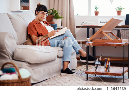 Woman, drawing and creative with book on sofa for sketch, artistic vision for tattoo company. Female illustrator, relax and home with pencil illustration for publication, design process and comic job Woman, drawing and creative with book on sofa for sketch, artistic vision for tattoo company. Female illustrator, relax and home with pencil illustration for publication, design process and comic job 143643389