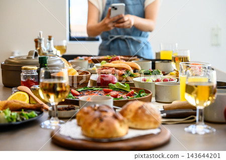 A woman taking pictures of food with her smartphone and a colorful dinner table. 143644201