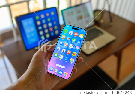 一個人手持智慧型手機,同時操作多個應用程式螢幕。 一個人手持智慧型手機,同時操作多個應用程式螢幕。 143644248