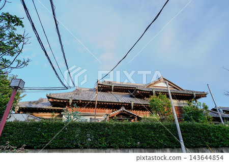 一棟宏偉的日式房屋，屋頂鋪著瓦片，在藍天下徐徐展開。 143644854