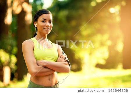 Fitness, portrait and woman with arms crossed in forest for training, running and cardio workout with music earphones. Sports, face or girl runner in park with power pose, exercise or radio streaming 143644866