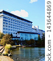 A modern hotel beautifully reflected in the blue sky and water, along with the autumn scenery. 143644869