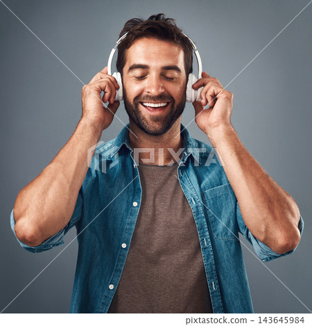 Face, man and headphone for hands in studio, audio media and podcast or ebook on gray background. Technology, streaming and music subscription for song, calm male person and smile for listening Face, man and headphone for hands in studio, audio media and podcast or ebook on gray background. Technology, streaming and music subscription for song, calm male person and smile for listening 143645984
