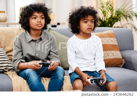 Children, video games and couch in living room for technology, controllers and entertainment in school holidays. Brothers, together and playing on sofa for bonding, gaming and esports in family home Children, video games and couch in living room for technology, controllers and entertainment in school holidays. Brothers, together and playing on sofa for bonding, gaming and esports in family home 143646262