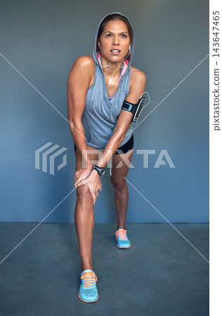 Fitness, stretching and woman with headphones in lunge for listening to music, streaming audio and radio. Sports, sweating and person warm up for training, exercise and workout on wall background 143647465