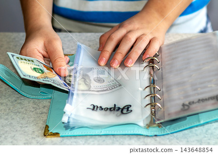 Person organizing cash deposit and budget in a turquoise planner with visible hands Person organizing cash deposit and budget in a turquoise planner with visible hands 143648854