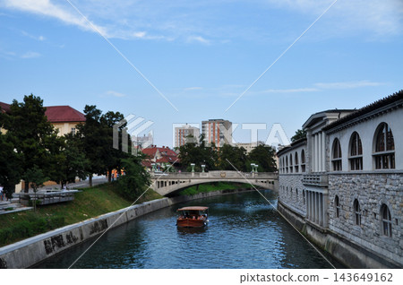A summer river with a stone arcade and a small bridge visible along the riverbank. A summer river with a stone arcade and a small bridge visible along the riverbank. 143649162