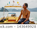 Thai longtail boatman navigating tropical sea with islands 143649928