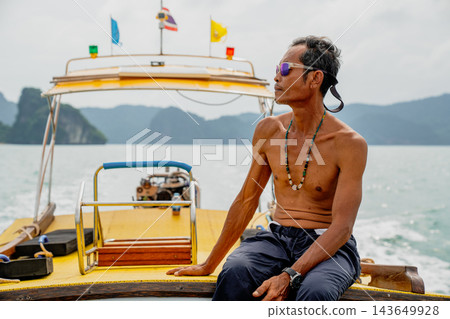 Thai longtail boatman navigating tropical sea with islands Thai longtail boatman navigating tropical sea with islands 143649928