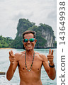 Smiling man giving peace sign on tropical vacation 143649938