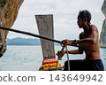 Thai longtail boat man adjusting rope 143649942