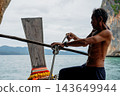 Thai man tying knot on longtail boat in ocean 143649944