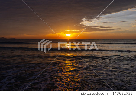 A golden sunset casts warm light across a calm ocean horizon, A golden sunset casts warm light across a calm ocean horizon, 143651735