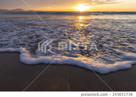 Warm golden sunset casts shimmering reflections across ocean waves 143651736
