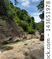 Rocky tropical stream flowing through a lush green jungle gorge 143651978