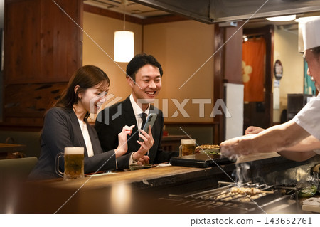 一男一女在吧台座位上享用烤雞串和啤酒。 一男一女在吧台座位上享用烤雞串和啤酒。 143652761