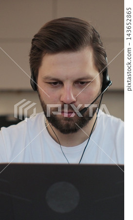 Vertical video. Portrait of a young man in home office. Caucasian man holding meeting with colleagues in home interior. Male manager looking on laptop. 143652865