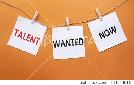 Talent Wanted Now text on white paper notes hanging on rope with clothespins over orange background. Recruitment and talent acquisition concept with copy space. 143653618