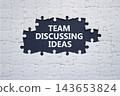 Team discussing ideas symbol. Concept words team discussing ideas on puzzle pieces. Team collaboration and brainstorming concept. Blue background. Copy space. 143653824