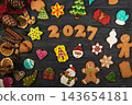 Christmas gingerbread cookies and holiday decorations forming year 2027 on colorful blue and pink wooden background 143654181