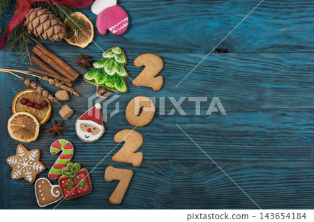 Festive gingerbread cookies for Christmas and New Year 2027 with spices and decorations on a dark wooden table 143654184