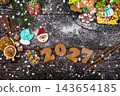 Festive gingerbread cookies for Christmas and New Year 2027 with spices and decorations on a dark wooden table 143654185