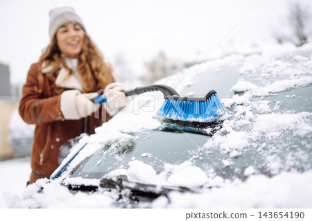 Cleaning snow from a car. Transport concept, seasonality Winter glass cleaning. 143654190